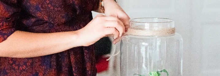 Person bindet Schnur um Glas